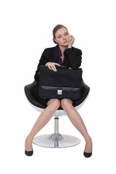 简朴的女商人坐着椅子公文包腿上