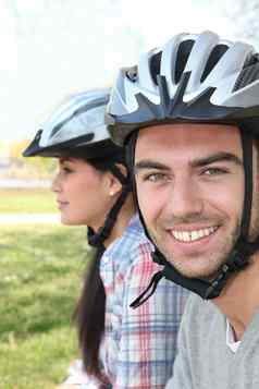 特写镜头拍摄夫妇骑自行车的人穿周期头盔