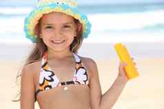 年轻的女孩海滩持有防晒霜