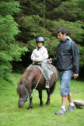 父亲帮助女儿骑小马
