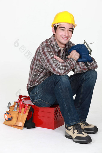 年轻的工匠坐着工具盒子