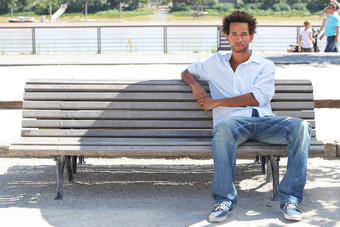 年轻的男人。坐着公共板凳上