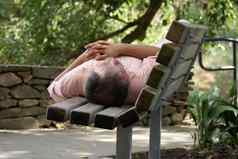 无家可归的人男人。睡觉公园板凳上