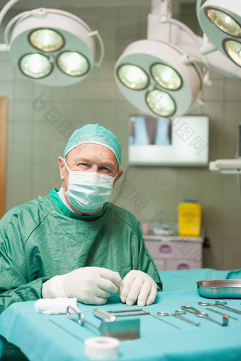 外科医生坐着前面外科手术工具