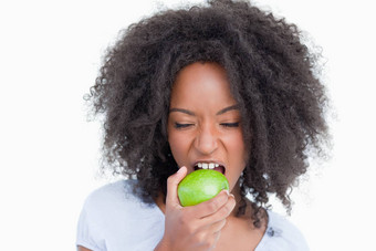 年轻的女人关闭眼睛吃绿色苹果