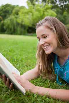 年轻的女孩阅读书公园笑