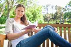 女人坐着公园板凳上书