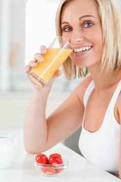 女人喝玻璃橙色汁微笑相机