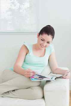 女人坐着沙发上阅读杂志