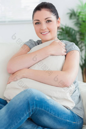女人坐着沙发上拥抱枕头
