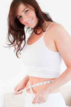 有吸引力的浅黑肤色的女人女人测量肚子磁带的措施