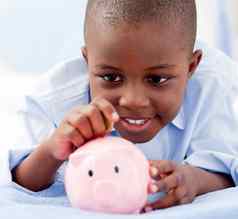 年轻的男孩床上把钱小猪银行