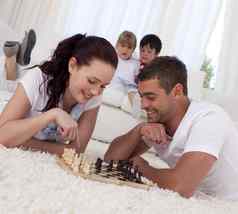 微笑夫妇玩国际象棋地板上起居室