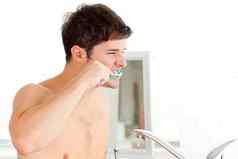 英俊的年轻的男人。刷牙牙齿浴室