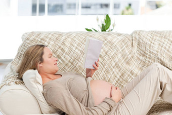 集中怀<strong>孕</strong>了女人阅读书说谎沙发上