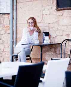 年轻的女人喝咖啡户外夏天