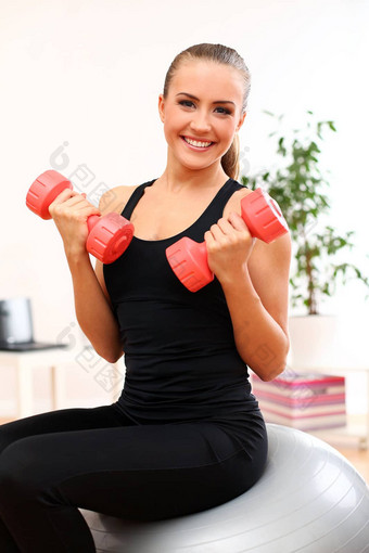 年轻的女人锻炼哑铃健身球