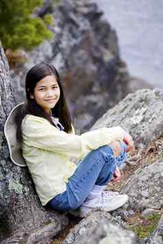 女孩坐着岩石悬崖边缘
