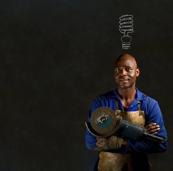 非洲黑色的男人。工业工人恩格里储蓄者黑板上背景非洲黑色的男人。工业工人能源储蓄灯泡黑板上