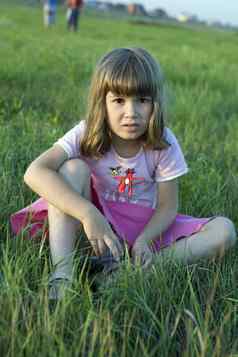 可爱的女孩坐着中间草地