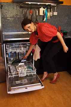 年轻的女人加载洗碗机现代厨房