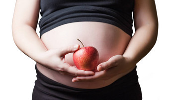 怀孕了女人持有红色的苹果手
