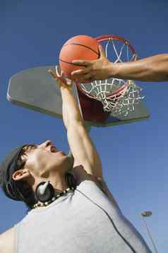 低角视图年轻的男人。玩篮球朋友蓝色的天空