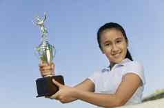 年轻的女孩网网球法院持有奖杯肖像低角视图
