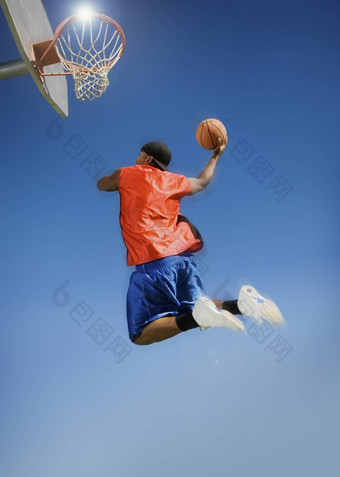 低角视图男人。扣篮<strong>篮球</strong>希望清晰的蓝色的<strong>天空</strong>