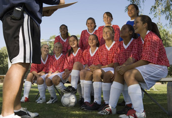 集团多民族的女足球球员听教练场