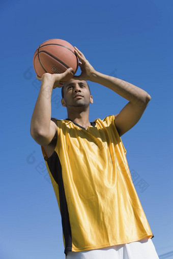 篮球球员扔球蓝色的天空