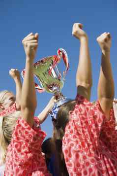 低角一边视图快乐女孩足球团队奖杯清晰的蓝色的天空