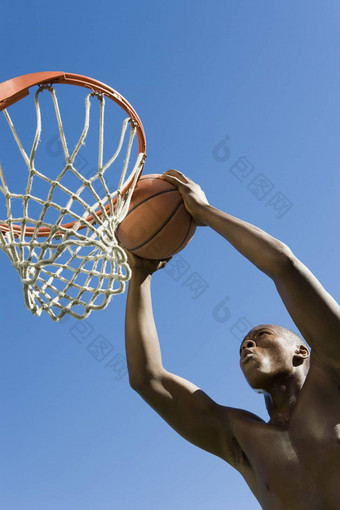 低角视图确定年轻的男人。<strong>扣篮</strong>篮球希望清晰的蓝色的天空