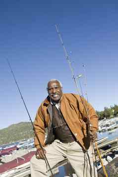 肖像快乐非洲美国男人。站钓鱼棒船背景