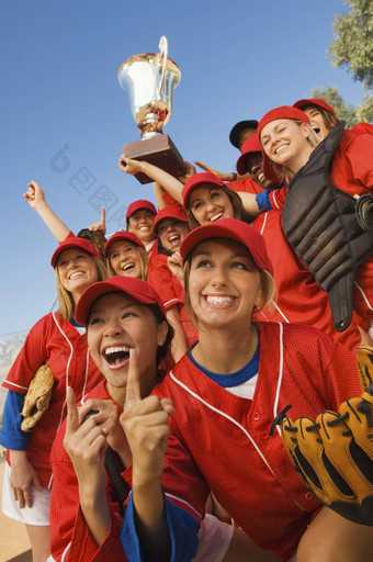 兴奋年轻的多民族女棒球团队欢呼赢得游戏