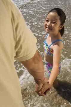 快乐女孩持有父亲的手海滩