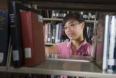年轻的亚洲女人书架子上图书馆