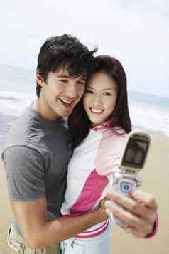 年轻的夫妇采取图片细胞电话海滩