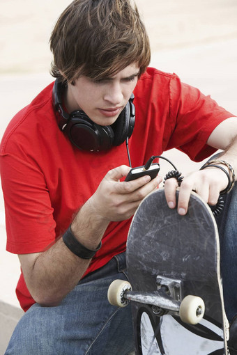 年轻的男人。滑板发短信消息细胞电话