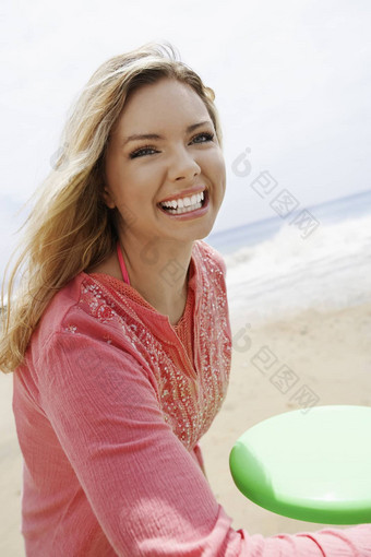 快乐的年轻的女人扔飞盘海滩