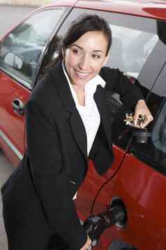 美丽的快乐业务女人西装加油红色的车燃料站