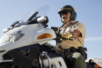 低角视图成熟的警察办公室骑摩托车