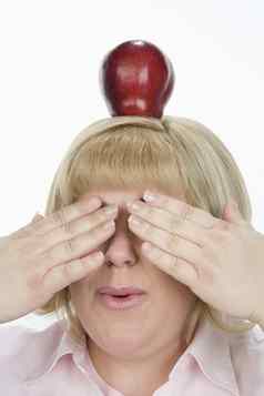 成熟的女人平衡苹果覆盖眼睛孤立的白色背景
