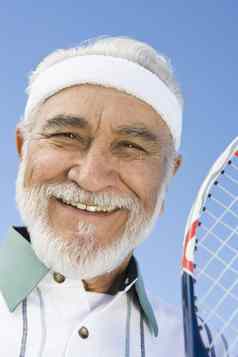 特写镜头肖像快乐高级男人。持有网球网拍天空