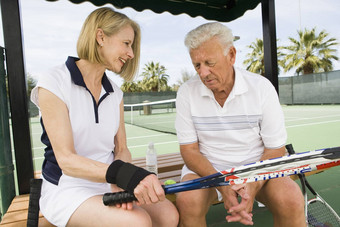 高级高加索人夫妇放松板凳上玩网球