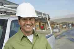 肖像微笑建设工人需要戴安全帽的站卡车建设网站