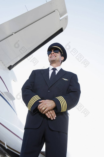 低角视图微笑飞行员统一的站飞机手紧握