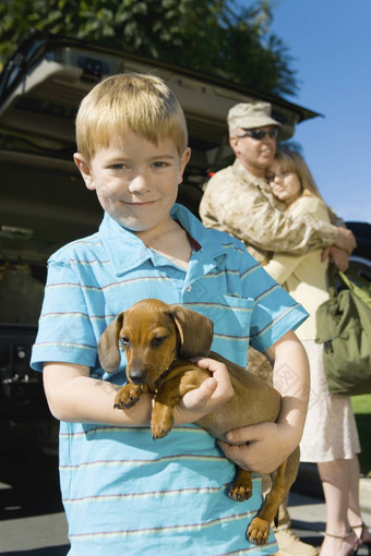 肖像快乐男孩携带狗父母拥抱背景