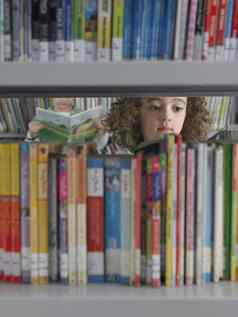 年轻的女孩选择书图书馆书架上男孩阅读书背景