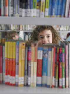 年轻的女孩选择书图书馆书架上男孩背景